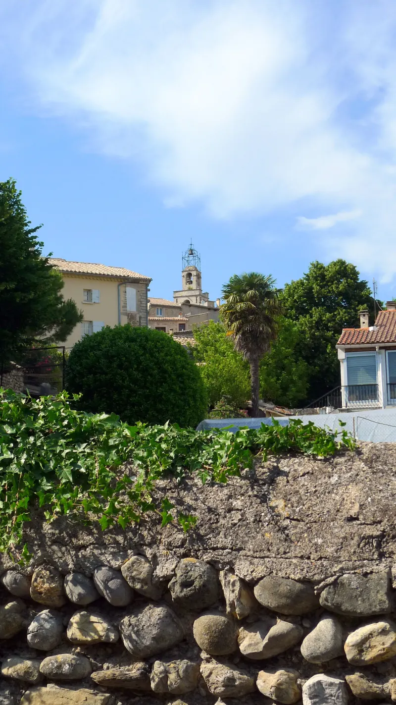 Un mur de pierres sèches et le clocher de Visan
